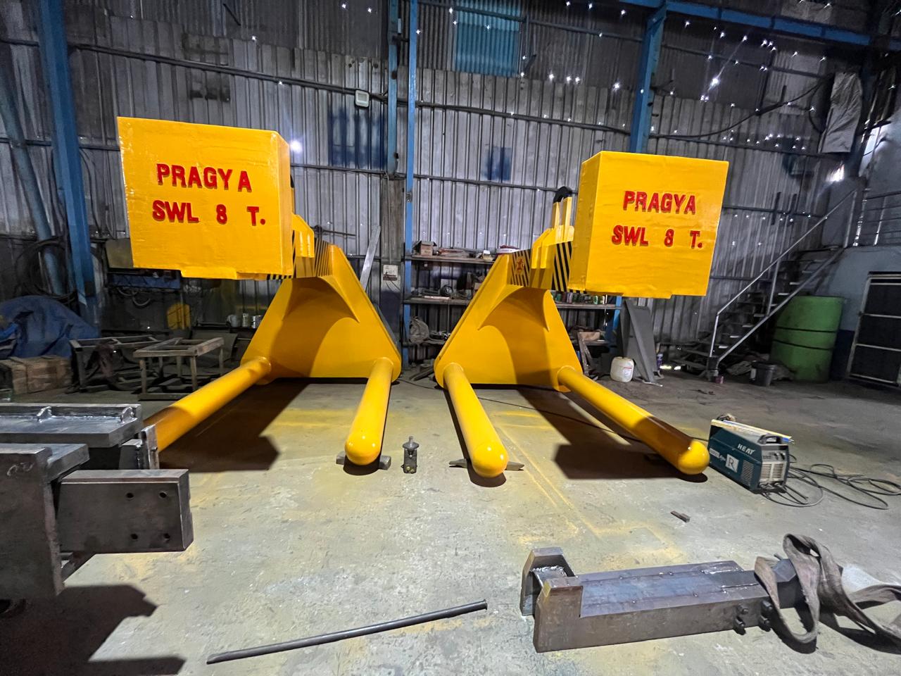 A matched pair of double coil C hooks marked PRAGYA SWL 8 T in the fabrication shop
